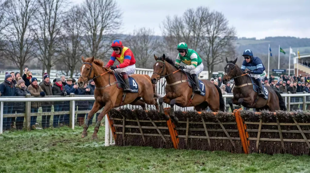 Horses and jockeys jumping a hurdle at Royal Windsor Racecourse on a crisp winter New Year