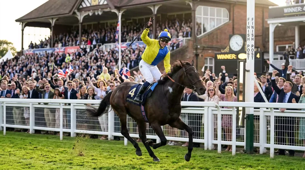 Jockey celebrating a winning ride past the post at Royal Windsor Racecourse with the grandstand crowd behind